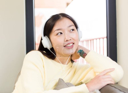 Téléchargez les photos : Asiatique jolie femme repos et écoute de la musique sur un canapé - en image libre de droit