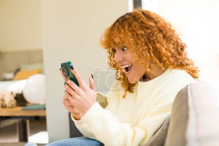 Téléchargez les photos : Young red hair latin pretty woman using a smartphone at home - en image libre de droit