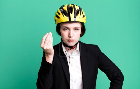 Foto de Young pretty woman making capice or money gesture, telling you to pay. bike and businesswoman concept - Imagen libre de derechos
