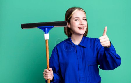 Photo for Young pretty woman feeling proud,smiling positively with thumbs up. windows washer concept - Royalty Free Image