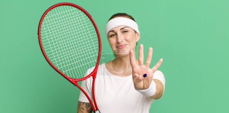 Foto de Joven bonita mujer sonriendo y buscando amigable, mostrando el número cuatro. concepto de tenis - Imagen libre de derechos