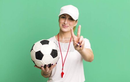 Téléchargez les photos : Jeune jolie femme souriante et sympathique, montrant le numéro deux. concept entraîneur de football - en image libre de droit
