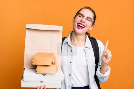 Foto de Pretty hispanic woman smiling and looking friendly, showing number one. delivery fast food take away concept - Imagen libre de derechos