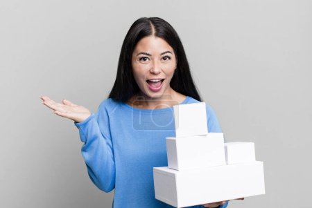 Photo for Hispanic pretty woman feeling happy, surprised realizing a solution or idea. with white boxes packagings - Royalty Free Image