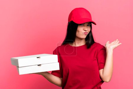 Photo for Hispanic pretty woman feeling puzzled and confused and doubting. delivery pizza concept - Royalty Free Image
