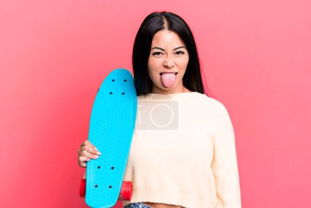 Foto de Hispanic pretty woman feeling disgusted and irritated and tongue out. skate boarding concept - Imagen libre de derechos