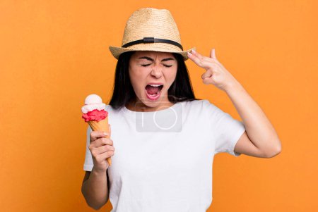 Photo for Hispanic pretty woman looking unhappy and stressed, suicide gesture making gun sign. ice cream and summer concept - Royalty Free Image