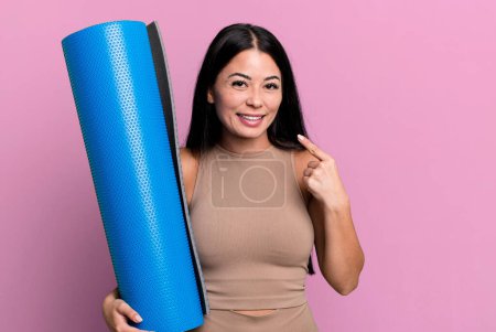 Téléchargez les photos : Hispanic pretty woman smiling confidently pointing to own broad smile yoga concept - en image libre de droit