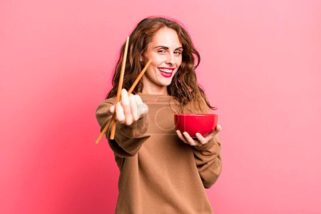 Photo for Hispanic pretty young woman eating a japanese noodles bowl. - Royalty Free Image
