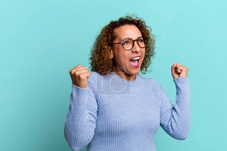 Photo for Middle age hispanic woman looking extremely happy and surprised, celebrating success, shouting and jumping - Royalty Free Image