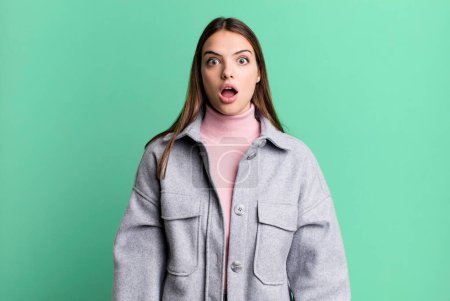 Foto de Pretty young adult woman looking very shocked or surprised, staring with open mouth saying wow - Imagen libre de derechos