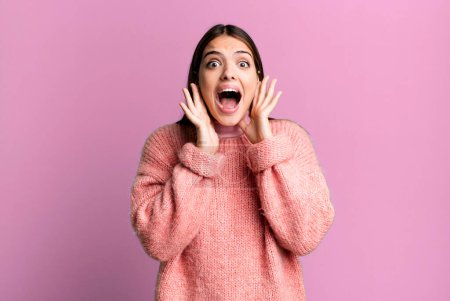 Photo for Pretty young adult woman screaming in panic or anger, shocked, terrified or furious, with hands next to head - Royalty Free Image