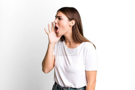 Photo for Pretty young adult woman yelling loudly and angrily to copy space on the side, with hand next to mouth - Royalty Free Image