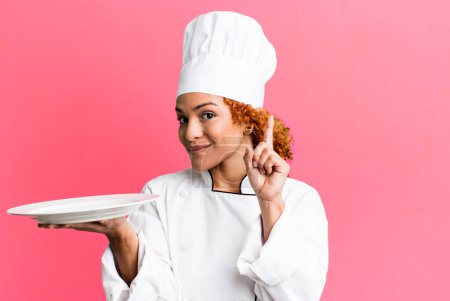 Téléchargez les photos : Cheveux roux jolie chef femme tenant un plat vide - en image libre de droit