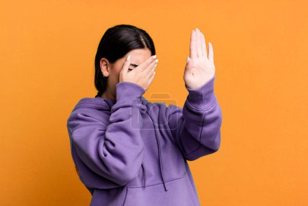 Photo for Covering face with hand and putting other hand up front to stop camera, refusing photos or pictures - Royalty Free Image