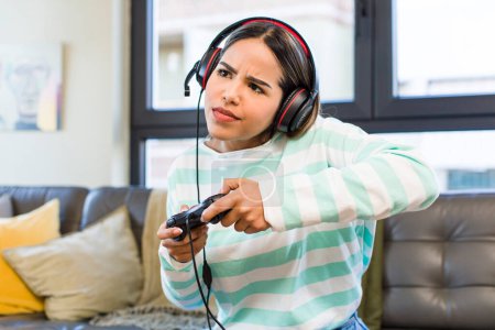 Téléchargez les photos : Pretty latin woman playing with headset and controller. gamer concept - en image libre de droit