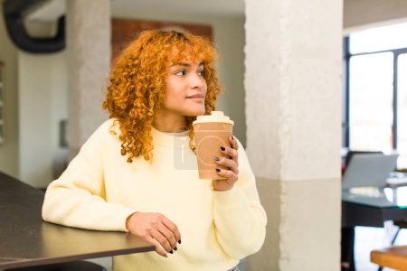 Téléchargez les photos : Jeune roux cheveux latins jolie femme avec un café chaud à la maison - en image libre de droit