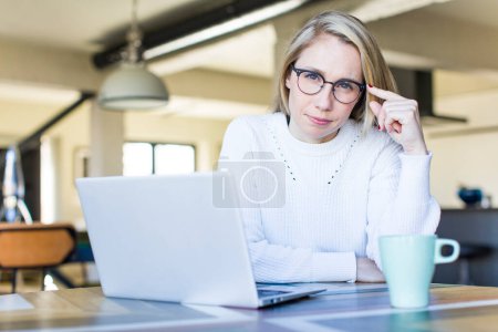 Foto de Young adult pretty blonde woman using her laptop al home - Imagen libre de derechos