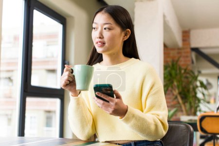 Foto de Asian pretty woman with a coffee cup at cool home - Imagen libre de derechos
