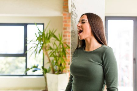 Photo for Young adult pretty woman screaming furiously, shouting aggressively, looking stressed and angry - Royalty Free Image