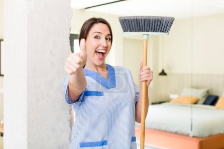 Photo for Young pretty woman feeling proud,smiling positively with thumbs up. housekeeper concept - Royalty Free Image