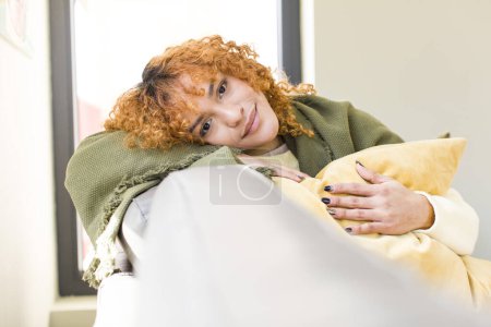 Téléchargez les photos : Young red hair latin pretty woman resting on a couch at home - en image libre de droit