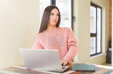 Foto de Pretty young woman with a laptop on a desk  at home - Imagen libre de derechos