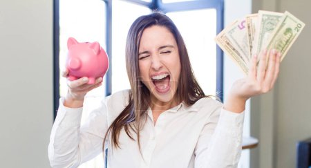 Téléchargez les photos : Young adult pretty woman with a piggy bank. money and savings concept - en image libre de droit
