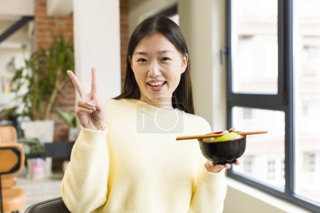 Foto de Asian pretty woman eating a ramen noodles bowl - Imagen libre de derechos