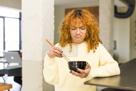 Téléchargez les photos : Young red hair latin pretty woman eating ramen noodle bowl at home - en image libre de droit