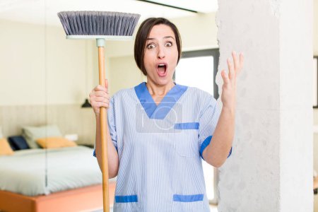 Téléchargez les photos : Young pretty woman feeling extremely shocked and surprised. housekeeper concept - en image libre de droit