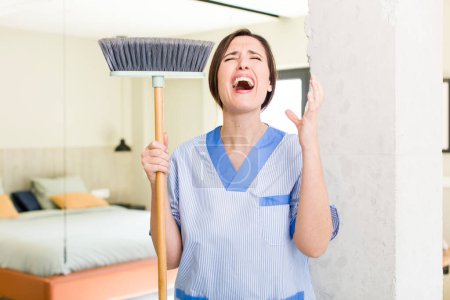 Foto de Young pretty woman looking desperate, frustrated and stressed. housekeeper concept - Imagen libre de derechos