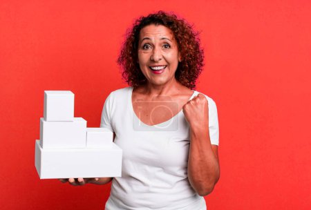 Photo for Pretty middle age woman feeling shocked,laughing and celebrating success. blank white boxes packaging - Royalty Free Image
