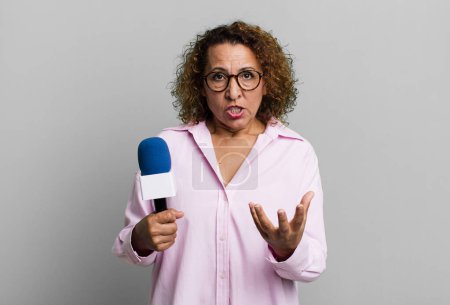 Photo for Pretty middle age woman looking angry, annoyed and frustrated. tv presenter with a microphone concept - Royalty Free Image