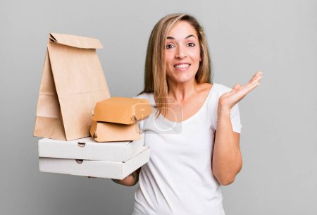 Foto de Pretty blonde woman feeling happy and astonished at something unbelievable. delivery take away food packages concept - Imagen libre de derechos