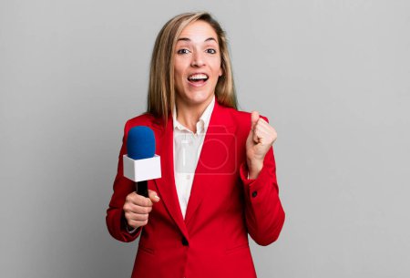 Foto de Pretty blonde woman feeling shocked,laughing and celebrating success. presenter with a microphone concept - Imagen libre de derechos