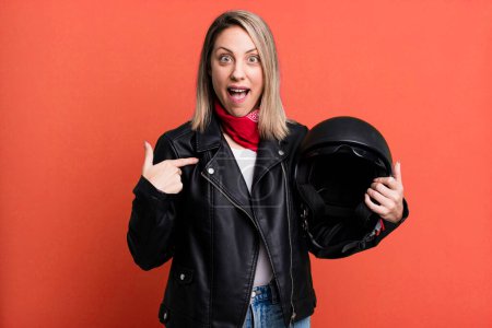 Photo for Pretty blonde woman feeling happy and pointing to self with an excited. motorbike rider and helmet concept - Royalty Free Image