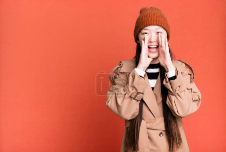 Photo for Pretty asian woman feeling happy,giving a big shout out with hands next to mouth - Royalty Free Image