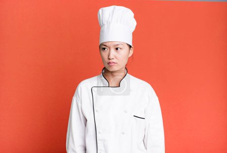 Photo for Pretty asian woman feeling sad, upset or angry and looking to the side. restaurant chef concept - Royalty Free Image