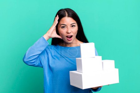 Photo for Hispanic pretty woman looking happy, astonished and surprised. with white boxes packagings - Royalty Free Image