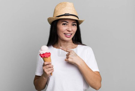 Téléchargez les photos : Hispanique jolie femme regardant excité et surpris pointant vers le côté. crème glacée et concept d'été - en image libre de droit
