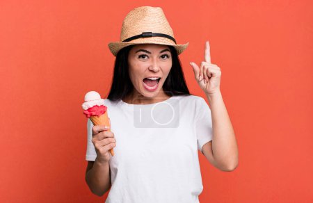 Foto de Hispanic pretty woman feeling like a happy and excited genius after realizing an idea. ice cream and summer concept - Imagen libre de derechos
