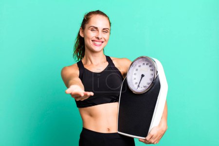 Foto de Hispanic pretty woman smiling happily with friendly and  offering and showing a concept. fitness, diet and weight scale concept - Imagen libre de derechos