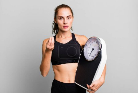 Foto de Hispanic pretty woman making capice or money gesture, telling you to pay. fitness, diet and weight scale concept - Imagen libre de derechos