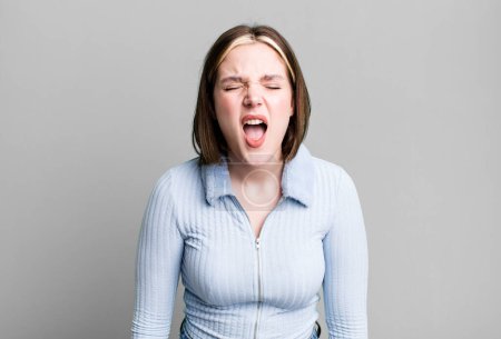 Photo for Young pretty woman shouting aggressively, looking very angry - Royalty Free Image