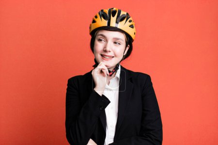 Photo for Young pretty woman smiling with a happy, confident expression with hand on chin. bike and businesswoman concept - Royalty Free Image