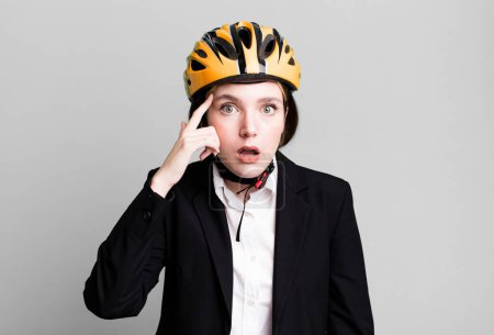 Photo for Young pretty woman looking surprised, realizing a new thought, idea or concept. bike and businesswoman concept - Royalty Free Image