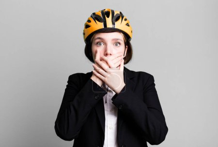 Photo for Young pretty woman covering mouth with hands with a shocked. bike and businesswoman concept - Royalty Free Image