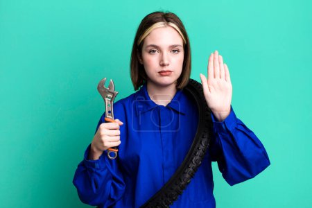 Photo for Young pretty woman looking serious showing open palm making stop gesture. bike mechanic concept - Royalty Free Image