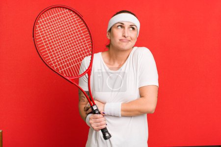 Téléchargez les photos : Jeune jolie femme haussant les épaules, se sentant confus et incertain. concept de tennis - en image libre de droit